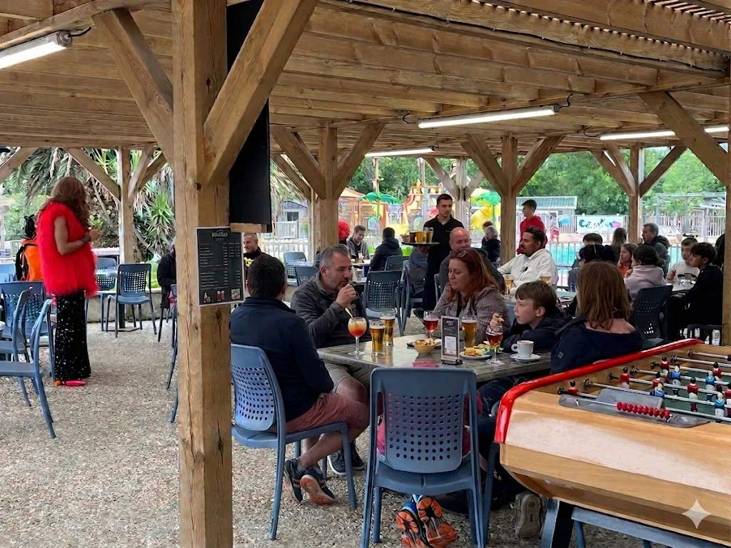 Familles trinquant à l'apéro sous la terrasse couverte du Warlop's avec babyfoot